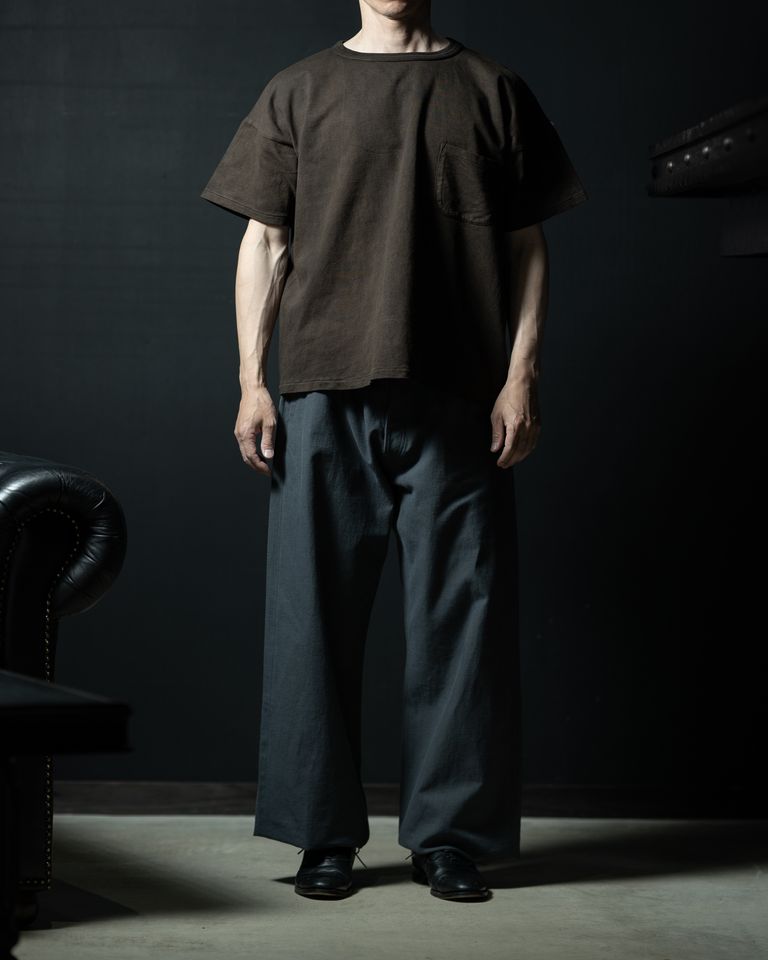 グレーのワイドパンツと合わせた全身コーディネート。泥染めのブラウンとグレーが渋みのある大人の配色を作り出す。ビッグシルエットのTシャツが腰にかかる着丈で、全体のバランスを整えている。