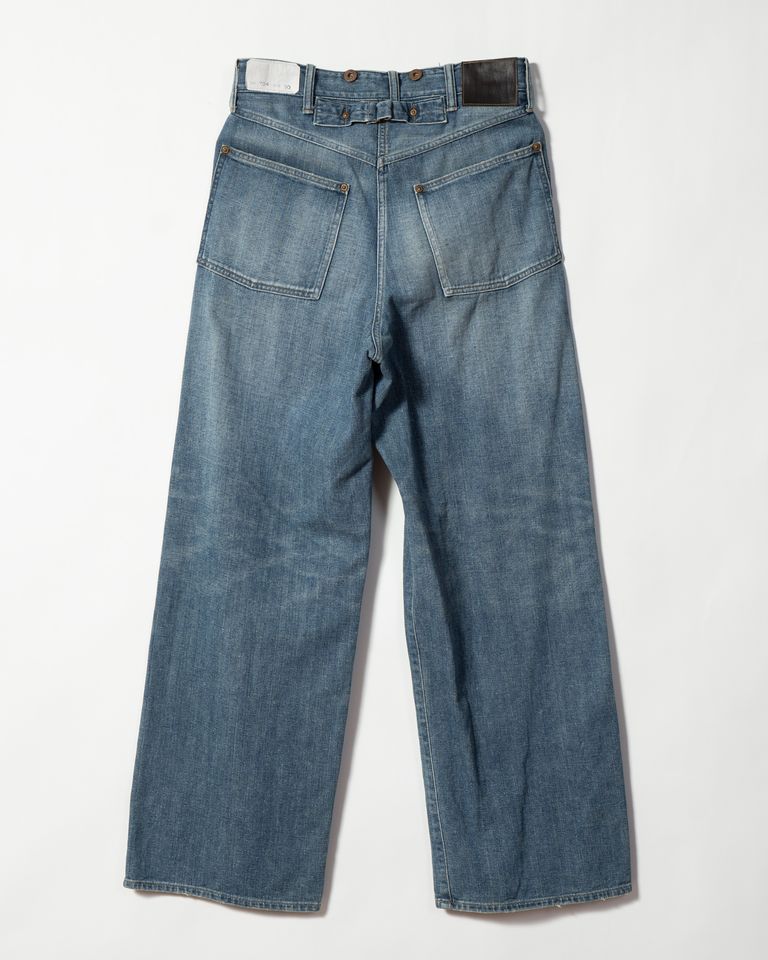 Taiga Takahashi のアイコニックアイテムでもある Lot.704 Demin Trousers c.1920s にダメージ加工を施したジーンズ。通常のダメージ加工に加え。塩縮加工を施すことで、生から穿いたような、シワ、ヒゲ等のユーズド感を実現した。錆びて朽ちたボタンとリベット、バックルが存在感を作り出している。