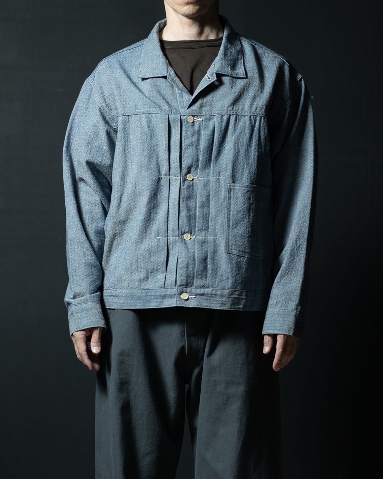 ボタンを全て留めたクローズスタイル。シャツとしても機能するデザインが活きており、貝ボタンの素朴な白とチャンブレー生地のインディゴブルーの対比が上品。フロントプリーツがきれいに整列する。