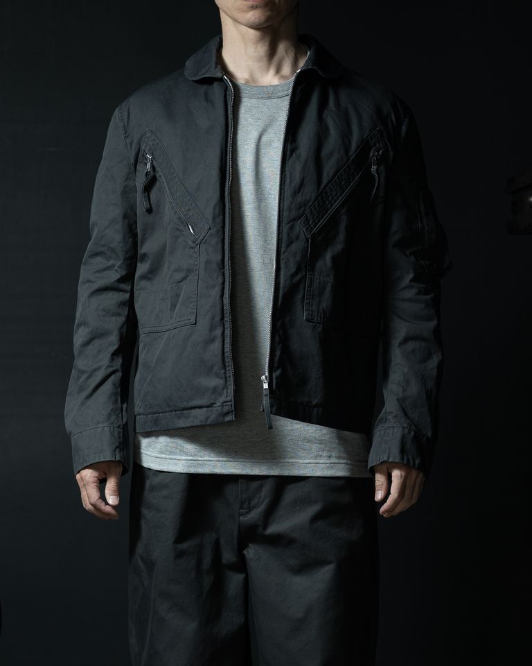 ミリタリーサマージャケットを再構築した〈YOUTH OF THE WATER〉のブルゾン。FINXギャバジンの滑らかな質感と軽やかな張りを活かし、テーラリングの技術で整えた端正なシルエットが特徴。バイオ加工による柔らかな風合いが加わり、日常に溶け込む静かな存在感を持つ一着です。