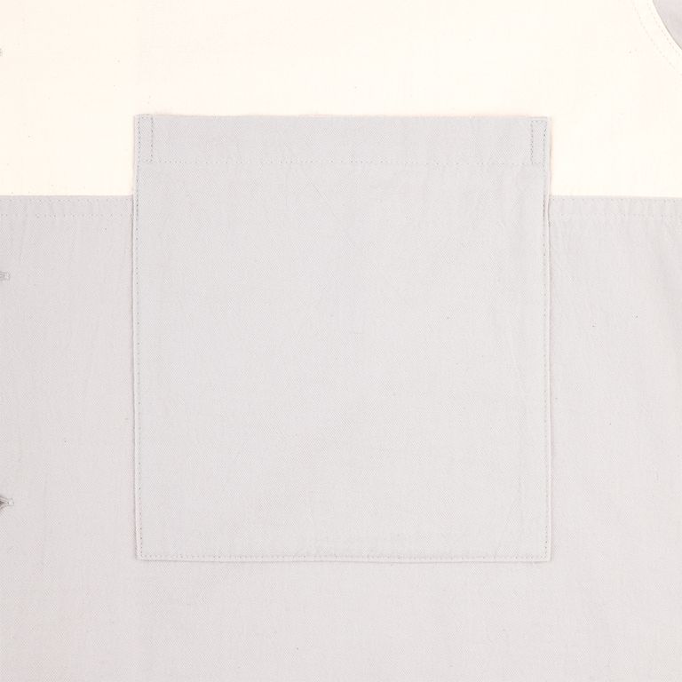 グレーのポケットディテール。ライトグレーとオフホワイトの境界をまたいで配置されたパッチポケットは、2色の生地の質感の違いを間近で確認できる見所でもある。ツイル地の細かな綾目が整然と並び、丁寧なステッチと相まって仕立ての良さを伝える。日常使いの中に宿る、C.Eらしい静かなこだわり。