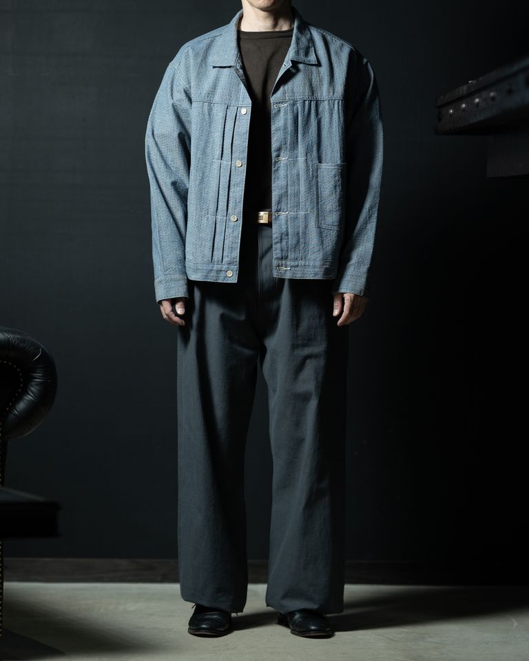 オープンスタイルでの全身コーディネート。肩傾斜のない平面的なシルエットが、ワイドパンツと相まって独特のボリュームバランスを生む。デニムとも異なる、シャンブレー特有の柔らかな青みがスタイリングの核となっている。