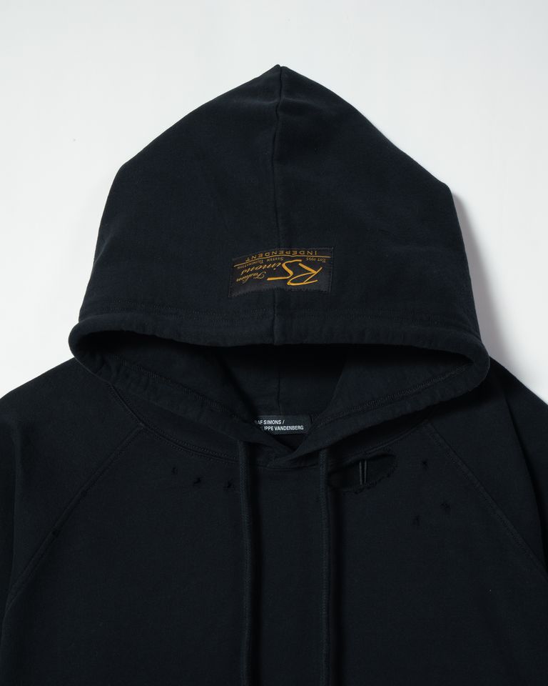RAF SIMONSの最後のコレクションは、フィリップ・ヴァンデンバーグの作品を特徴としたビッグシルエットのフーディです。コットン100%、トルコ製で、ダメージ加工とヴィンテージ加工が施されています。フードにはRAF SIMONSのワッペン、ラグランスリーブ、袖と裾にたくしあげ用フックがあり、独特のデザインと機能性を兼ね備えています。