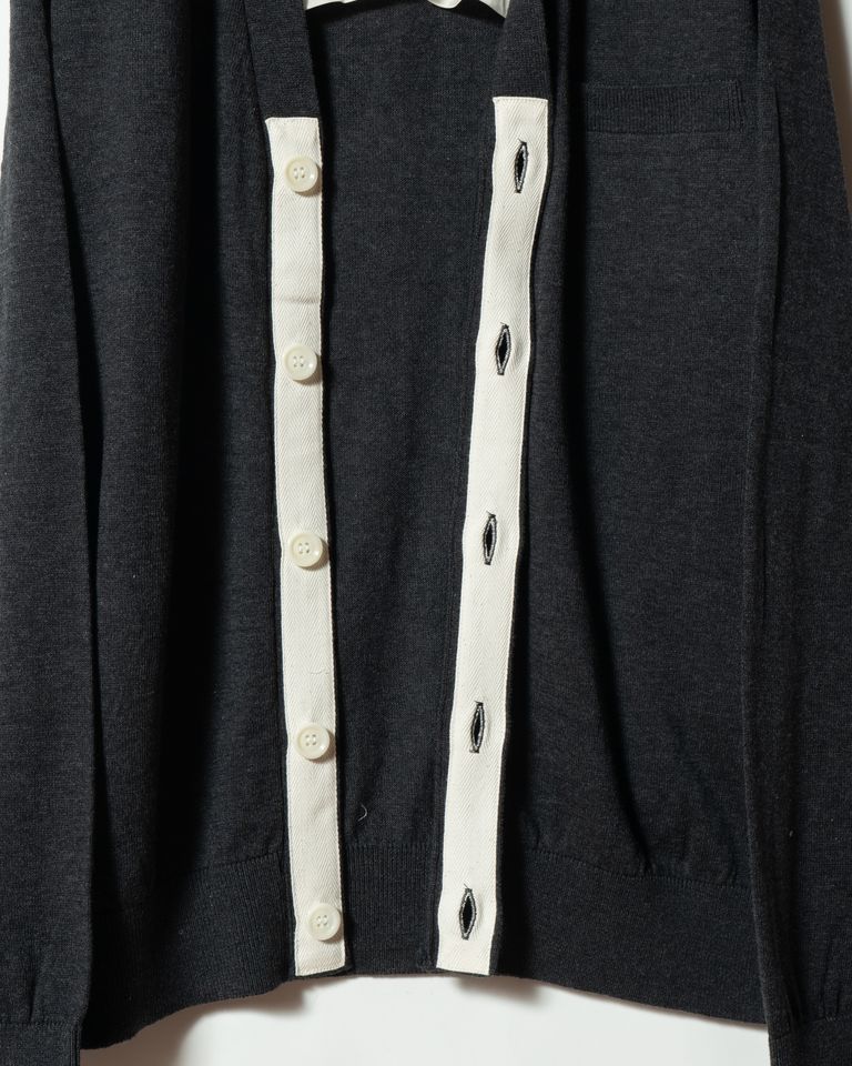 前立て裏には布帛をあて、強度と立体感を確保。ニットでありながらジャケットのような構造を持たせています。ボタンホールの仕立ても丁寧です。