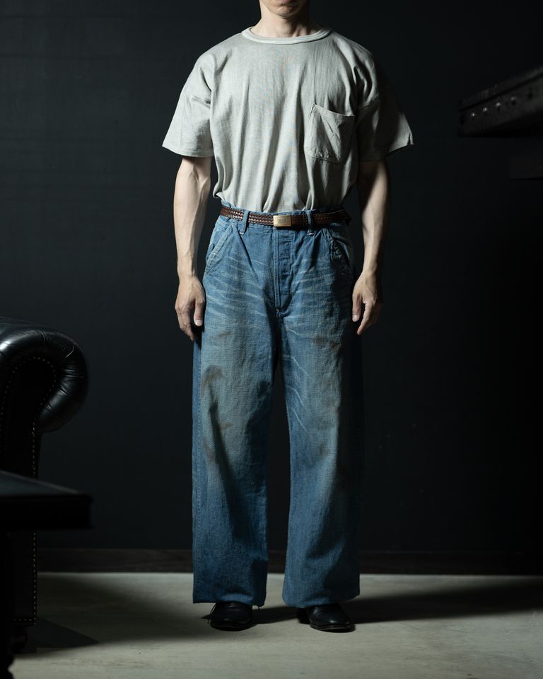 タックインスタイルの全身カット。ヴィンテージ感のある色落ちしたインディゴデニムと墨染めTシャツが経年変化同士の相性の良さを示す。