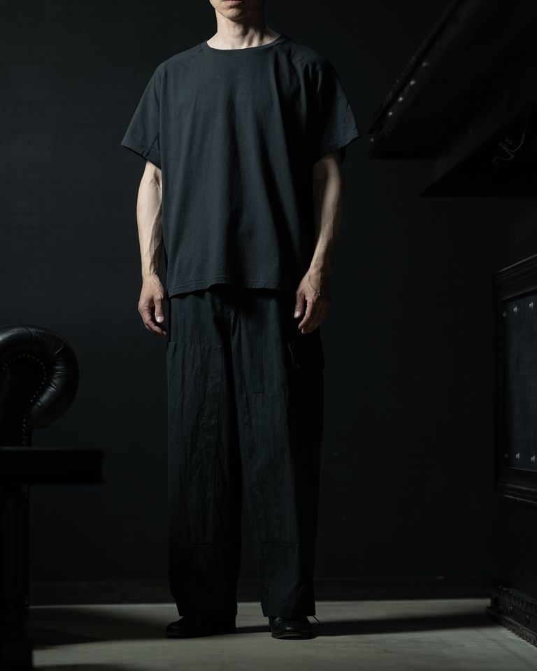 ワイドなパンツと合わせたスタイリング。着丈が短めでヘムがすっきりしているため、ボリュームのあるボトムスとの相性が良い。上下ともにダークトーンでまとめることで、Tシャツでありながらきちんとした印象のコーディネートに仕上がっている。モデル着用サイズ4。
