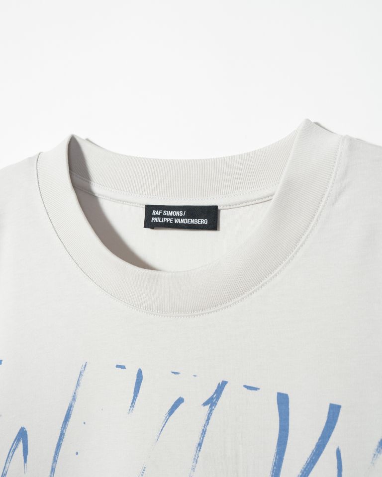 ラフシモンズ(Raf Simons)は、ベルギー出身のデザイナーであり、フィリップ・ヴァンデンバーグの作品に着想を得た最後のコレクションを発表しました。ヴァンデンバーグの作品は、強烈な筆致や濃い色調が特徴的であり、社会批判や政治的な問題に対する彼の強い思いが表現されています。ラフシモンズは、この個性的で強烈なグラフィックをアイテムに落とし込み、ラフシモンズらしい洗練されたデザインと融合させました。