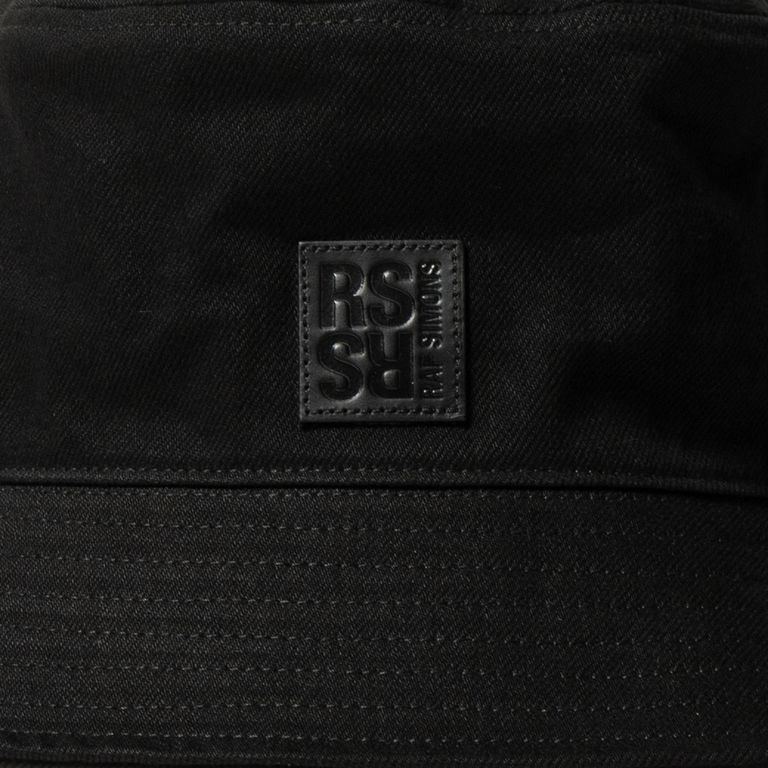 RAF SIMONSのデニムバケットハットは、シンプルクラシックなデザインに、洗練された印象を与えるRSレザーパッチを添えています。コットン100%のデニム生地を使用し、イタリア製で高品質な仕上がりとなっています。ファッション性と機能性を兼ね備え、様々なスタイルや場面に合わせてコーディネートすることができます。 日差しや風雨から頭部を守るアイテムとしても活躍するため、実用的な一面もあります。