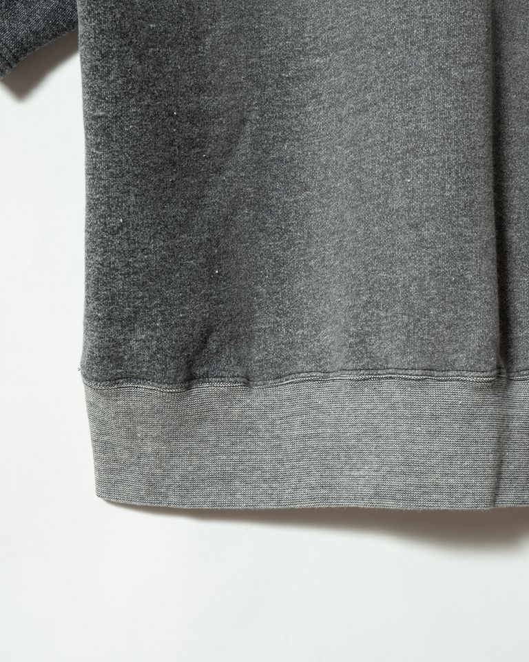 裾のリブは本体と異なる編み目で仕上げられ、素材感のコントラストが生まれている。ロンガリット加工により本体とリブで色落ちの差が生じ、長年着込んだような自然なグラデーションを演出。このディテールひとつに1950年代ワークスウェットへのリスペクトが宿る。