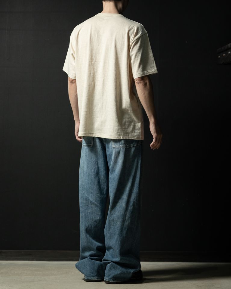 Taiga Takahashi のアイコニックアイテムでもある LOT.616 Tee Shirt をベースに脇下の溜まりを改良するため肩傾斜をつけて再構築した。素材は手紡ぎのような風合いの天竺。明治時代に発明された国産紡績機のガラ紡で紡がれた糸を現代の技術で再現した糸を使用している。この糸は、通常の紡績糸に比べ低速で紡績することで、空気を含み軽く優しい風合いに仕上がる。