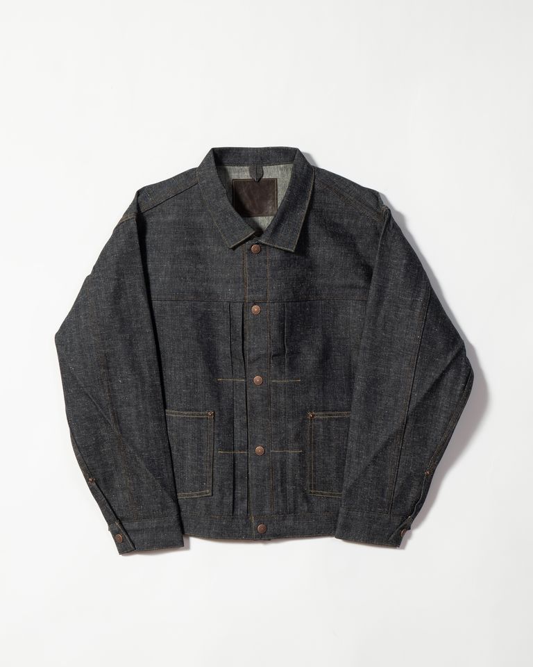 Taiga Takahashi のアイコニックアイテムでもあるデニムジャケット。米国産オーガニックコットンを使用し、岡山にある旧式力織り機で織り上げた 3/1 左綾、ライトオンスデニム。現代の織り機の10〜20分の1という低速度でしか織ることができないシャトル織り機とも呼ばれる旧式力織り機でゆっくりと織り上げたデニム生地は、綿糸本来の凹凸が残り、いい意味でムラができる。
