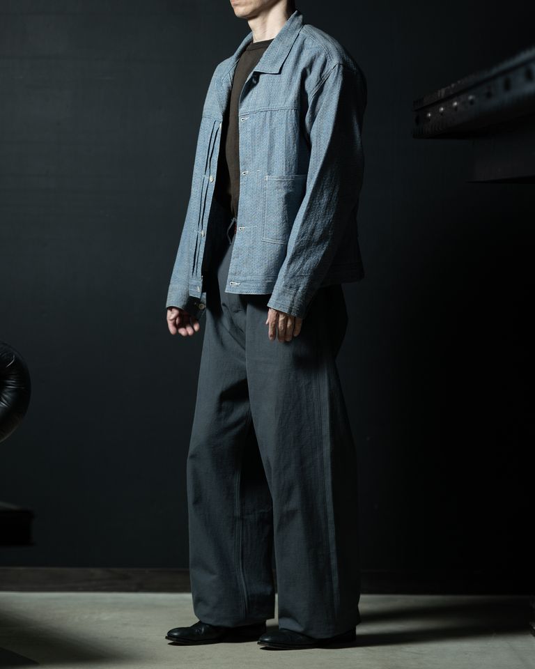 サイドから全体を捉えたショット。ジャケットの裾丈とワイドスラックスの組み合わせが、重心を中央に保ちながらも抜け感のあるシルエットを構成。ブラックシューズが全体を引き締めている。