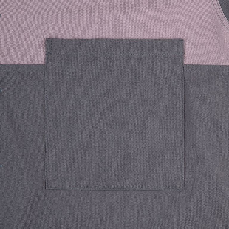 前身頃のパッチポケットは、上下の切り替えラインと一体となったデザイン。ステッチが生地の境界を縁取り、パネル構成の立体感を際立てる。コットンツイルの織り目が表情豊かで、チャコールの深みある色合いが精度の高い縫製をより引き立てている。実用性とデザイン性を兼ね備えたディテール。