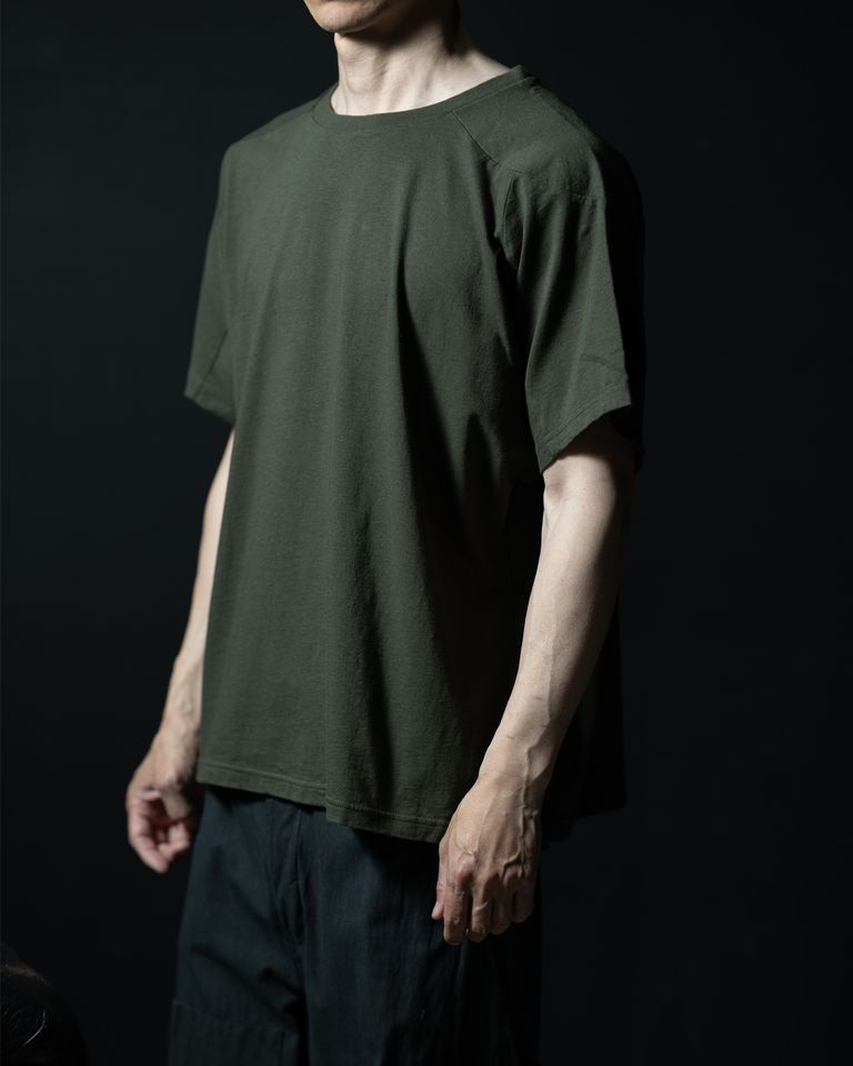 ドルマン調の袖がどのように体に沿うかがわかるアングル。腕を自然に下ろした状態でも袖口が体側に近い位置に収まり、すっきりとした印象を保つ。ショルダーの切り替えラインが斜め視点でも確認でき、立体的なパターンが着用状態でも機能していることが伝わる。