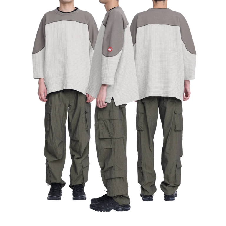 100%コットン。ガーゼ生地。プルオーバー。クルーネック。後ろ身頃ショルダーに刺繍でCAVEMPT。左袖上部にシリコンパッチ。身頃上部で色・生地切り替え。切り替え部分にパイピング。裾脇にスリット。ワイドシルエット。ウォッシュ加工。日本製。