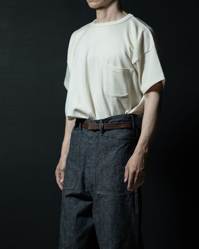 横から見たタックインスタイル。Tシャツのインした裾がウエスト周りに自然な膨らみを作り、デニムのハイライズラインを引き立てる。ブレイデッドベルトの編み込みディテールがアクセントに。