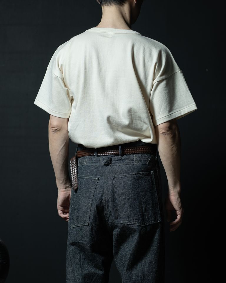 背面上半身のタックインカット。ブレイデッドレザーベルトがデニムのウエスト部分をしっかりと引き締め、後ろ姿にも着こなしへの配慮が光る。Tシャツの裾のはみ出し具合が絶妙なバランス。