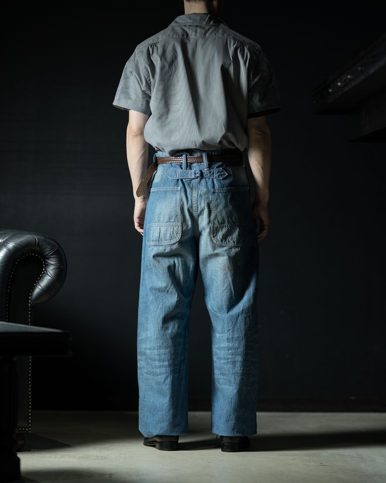 バックスタイルの全身カット。バックルとパッチポケットが要所を引き締め、極太シルエットの中にも構築的な美しさが宿る。セットアップ対応のジャケットとの合わせも楽しみたい。