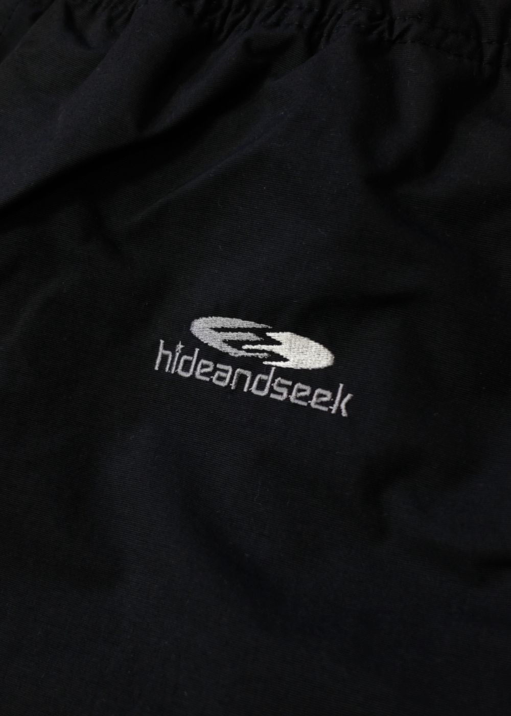 HIDE AND SEEK - NYLON TRACK PANTS (BLACK) / ナイロントラックパンツ