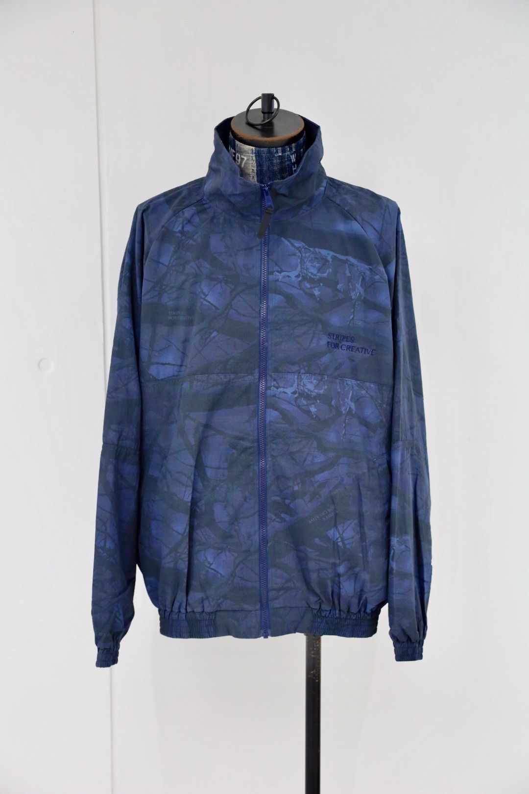 S.F.C 25FW エスエフシー WINDBREAKER JACKET (REAL TREE CAMO) (SFCFW25J06)Navy Tree Camo