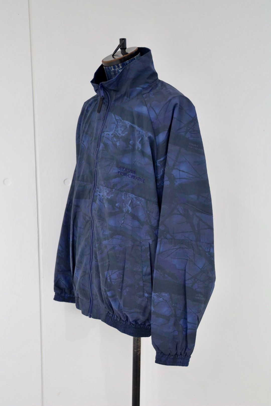 S.F.C 25FW エスエフシー WINDBREAKER JACKET (REAL TREE CAMO) (SFCFW25J06)Navy Tree Camo