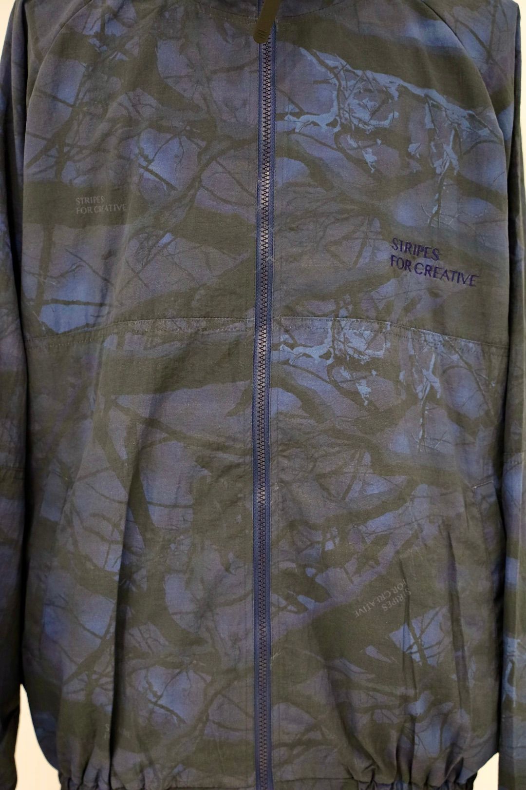 S.F.C 25FW エスエフシー WINDBREAKER JACKET (REAL TREE CAMO) (SFCFW25J06)Navy Tree Camo