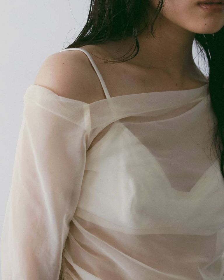 片側のみ肩をのぞかせるオフショルダーデザインで、さりげなく女性らしさを添える一枚。