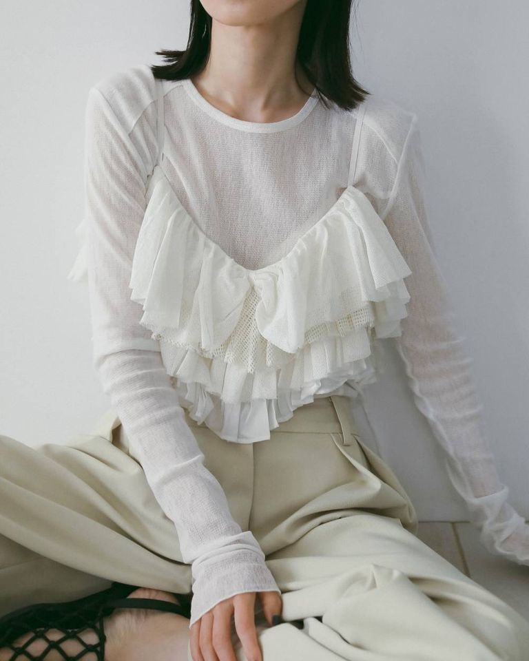 ボリュームのあるフリルが、シンプルなTシャツに重ねるだけでスタイリングを華やかな印象に。
肩紐は後ろで結んで長さの調節が可能。